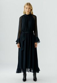 Schwarzes, langärmliges Kleid mit hohem Kragen, durchsichtigen Ärmeln und einem gerafften Saum; verfügt über eine taillierte Taille und eine fließende Silhouette.