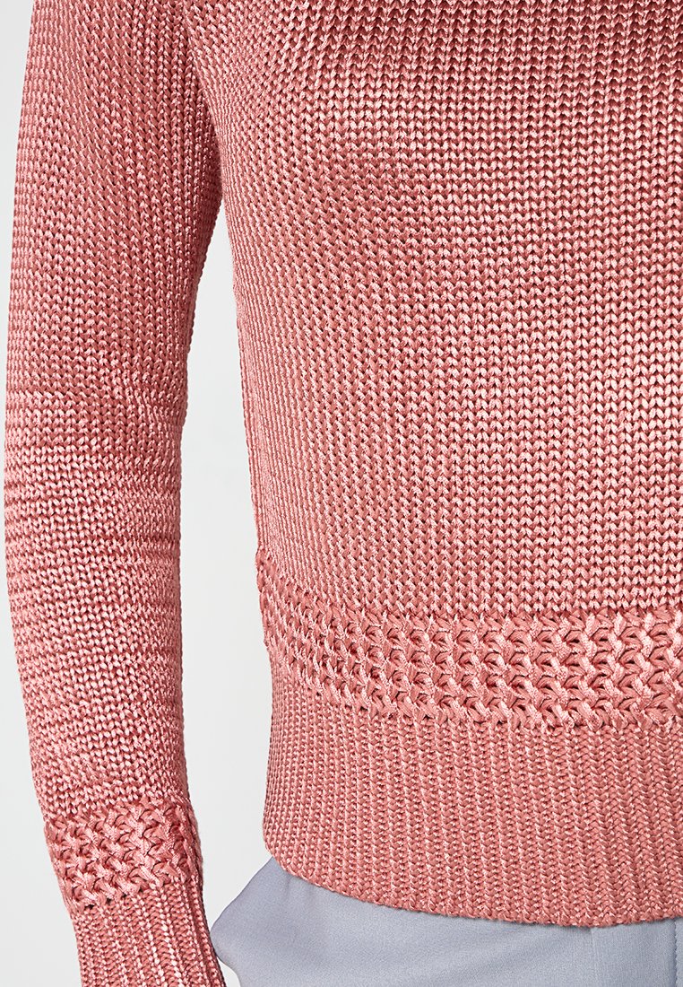Maglione lavorato a maglia in rosa pallido con cuciture testurizzate, orlo intrecciato e maniche lunghe, realizzato in un tessuto morbido adatto per essere indossato a strati.