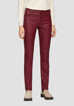 Pantalons en simili cuir bordeaux avec une coupe slim, design à cinq poches, léger brillant et des bottes de couleur claire en contraste.