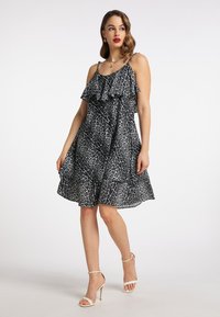 Rochie cu imprimeu leopard alb-negru, cu decolteu cu volan, bretele subțiri și fustă evazată, asortată cu sandale albe cu bretele.