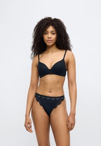 Zwarte lingerieset met een gladde, diepe bh met verstelbare bandjes en een bijpassende string met kanten accenten en een tailleband met logo.