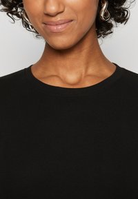 Black ribbed t-shirt with a crew neck. The fabric appears soft with a smooth texture, showcasing a simple, clean design.
