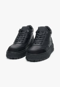 Czarne sneakersy za kostkę wykonane z gładkiej skóry i zamszu, wyposażone w grube, teksturowane gumowe podeszwy, sznurowanie z przodu oraz wyściełane kołnierze.