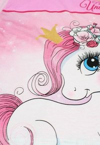 Tissu rose avec une licorne de dessin animé ayant des yeux bleus détaillés, une crinière rose tourbillonnante, une couronne dorée et des accents floraux. Fond scintillant.