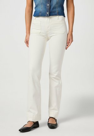 Witte rechte jeans met twee voorkeurszakken en een hoge taille, gecombineerd met een denim shirt en zwarte flats. Zachte textuur, minimalistische details.