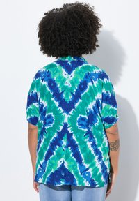 Bluzka z krótkim rękawem w intensywnym wzorze tie-dye, obejmująca kolory zielony, niebieski i biały; lekka, teksturowana tkanina o luźnym kroju.