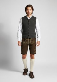 Grijze wollen gilet met knopen, wit shirt, bruine shorts met bloemborduursels, crème kniekousen en donkerbruine schoenen.