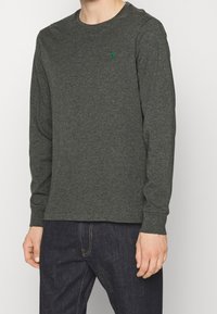 Långärmad skjorta i mörkgrå bomullsblandning, med rund halsringning och en liten grön logotyp på bröstet. Slät textur, figurnära design.