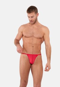 Punaiset thong-alushousut, jotka on valmistettu sileästä kankaasta, ja joissa on minimalistinen muotoilu ohuilla sivuilla ja kapealla vyötärönauhalla.