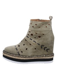 Bota de tobillo de ante beige con patrones geométricos recortados, acentos negros, bordes cosidos y una suela de estilo yute tejido. Cuenta con una cremallera.