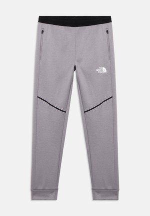 Halványszürke, szűkített szárú melegítőnadrág fekete derékpánttal, cipzáras oldalzsebekkel, fekete átlós csíkokkal és fehér The North Face logóval a jobb combon.