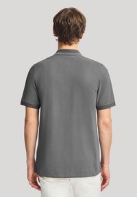 Grå pikétröja med mjuk textur, korta ärmar och en klassisk kragsdesign. Har diskret sömnad och en avslappnad passform.