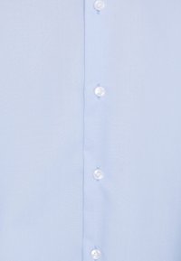 Jasnoniebieska tkanina koszulowa z pionowym rzędem czterech białych guzików zapinanych pośrodku.