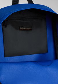 Zaino blu con tessuto testurizzato, dotato di una tasca con zip nera e un'etichetta che riporta "NAPAPIJRI" in caratteri bianchi e arancioni.