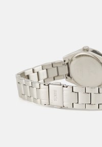 Silver stainless steel wristwatch featuring a linked bracelet design and a brushed finish, with a polished clasp engraved with the brand name.