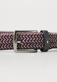 Woven belt in black with red and white accents; features a silver metal buckle and a black leather keeper with logo detail.