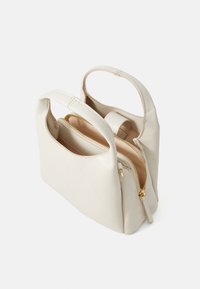 Sac à main en cuir beige avec deux poignées arrondies, un compartiment zippé et une texture lisse. Équipé de quincaillerie à fermeture éclair en ton doré.