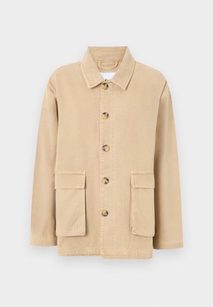 Giacca beige in cotone con chiusura a bottoni, colletto appuntito e due tasche a pattina anteriori. Presenta una vestibilità rilassata e dettagli di cucitura.