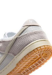 Hvid og beige Nike sneakerhælk med tekstureret stofforst og gummisål med geometrisk slidmønster.