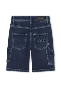 Pantaloni cargo in denim blu scuro con cinque tasche, passanti per cintura e un'etichetta nera. Texture usurata lungo i bordi e le cuciture.