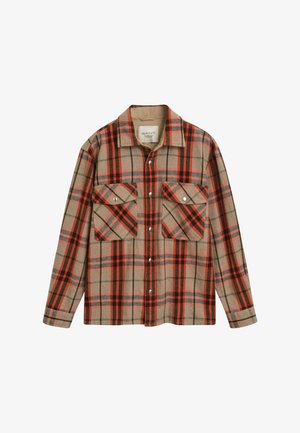 Chemise en flanelle avec un motif à carreaux beige, rouge et vert. Manches longues, deux poches avant avec fermetures à pression et un col.