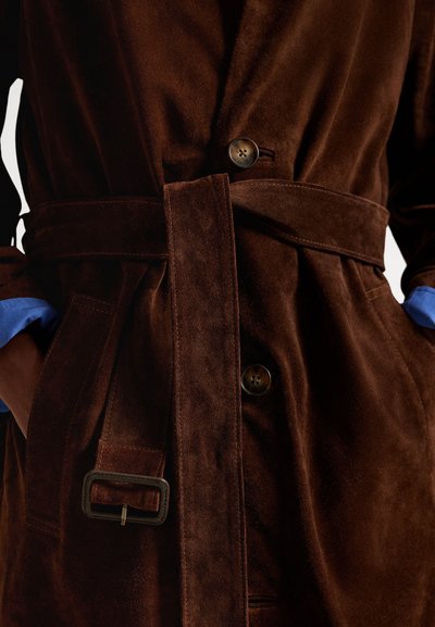 Hnedý semišový kabát s opaskom v páse, so zapínaním na gombíky a modrými akcentmi na rukávoch. Jemná textúra a prispôsobený strih.