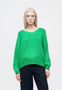 Πράσινο πλεχτό πουλόβερ με φαρδύ λαιμό, χαλαρή εφαρμογή και ριμπ μανσέτες. Συνδυασμένο με σκούρα μπλε, φαρδιά παντελόνια. Υφασματισμένο νήμα.