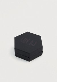 Šesťuholníková čierna kartónová škatuľa s nápisom „LUV AJ“ vytlačeným tmavým písmom. Povrch má textúrovaný vzhľad. Jednoduchý dizajn bez ďalších ozdôb.