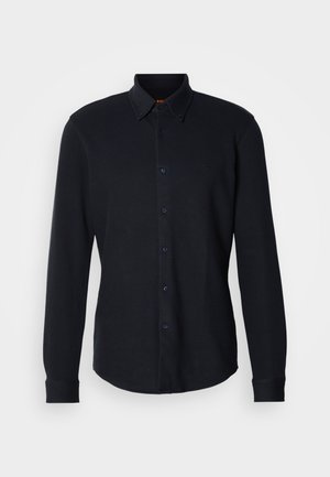 Donkerblauw langarmshirt van een gestructureerde stof, met een button-down kraag, knopen aan de voorkant en een subtiel logo op de borst.