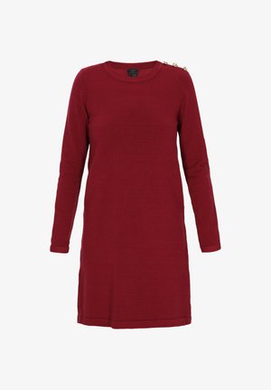 Šaty s dlhým rukávom a okrúhlym výstrihom z tmavočervenej pleteniny. Obsahujú zlaté gombíky na pleci, majú rovný strih a rebrované manžety.