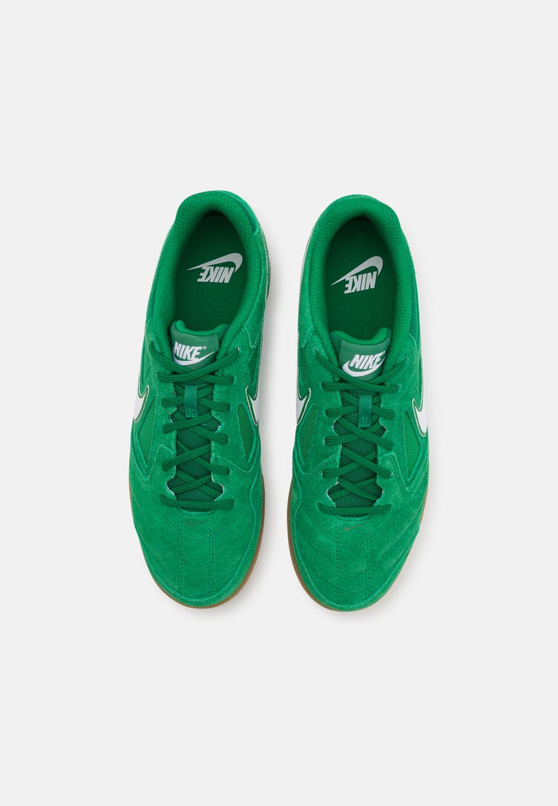Zapatillas deportivas de ante verde con el logo blanco de Nike, diseño de cordones, cuello acolchado y suela de goma. La vista superior muestra una textura detallada.