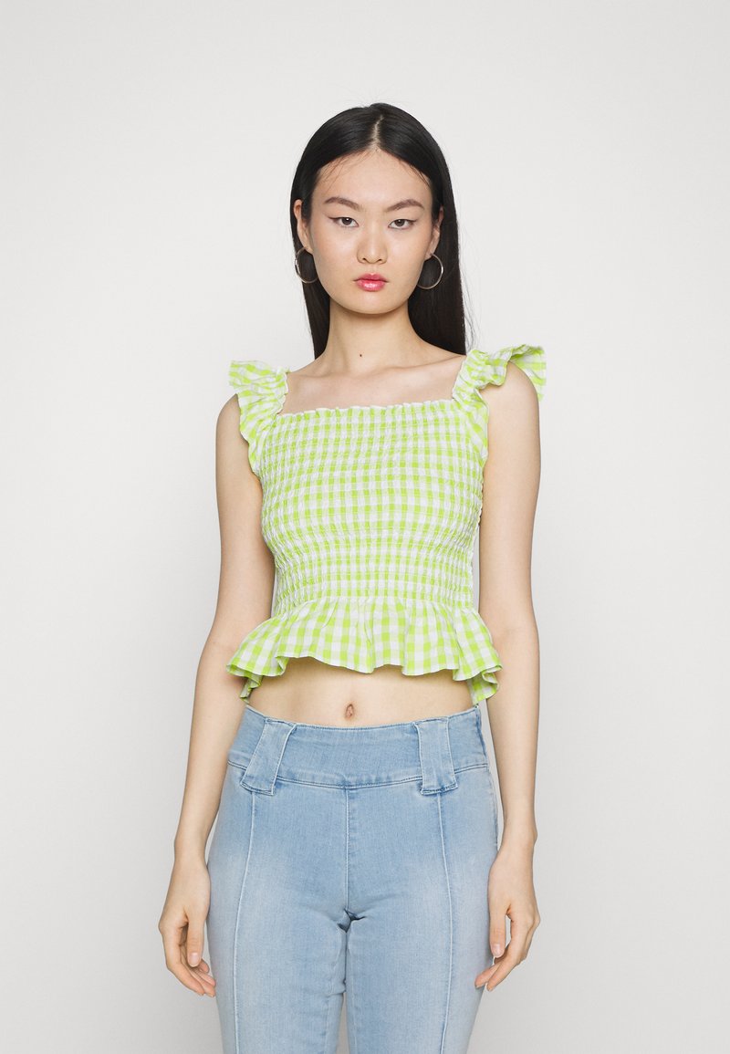 Top cropped de gingham verde com alças franzidas, corpete pregueado e bainha em peplum. Combinado com jeans de cintura alta azul claro.
