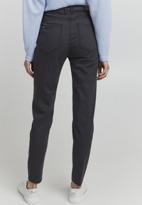 Donkergrijze skinny jeans met achterzakken, gemaakt van denim, met een middelhoge taille en een schone, minimalistische uitstraling. Gestyled met witte sneakers.