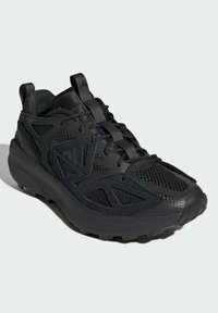 Scarpe sportive nere caratterizzate da una combinazione di materiali lisci e a rete, un collo imbottito, dettagli testurizzati e un design della suola robusto.