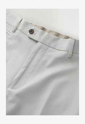 Šviesiai pilkos kelnės su rudu mygtuku, diržo kilpelėmis ir matomu priekinio kišenės detalizavimu ant vientisos fono.