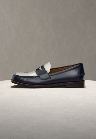 Męskie skórzane penny loafer z czarno-białym blokowaniem kolorów, niskim obcasem i przeszywanym noskiem mokasyna, prezentowane na jasnej powierzchni.