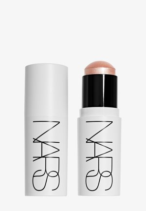Crayon de maquillage NARS avec un boîtier blanc et un logo noir, montrant un bouchon fermé à gauche et un bâton ouvert avec une teinte pêche scintillante à droite.
