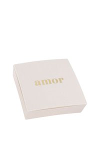 Scatola quadrata di un pallido rosa con angoli arrotondati; testo dorato in rilievo "amor" sulla parte superiore; superficie liscia, design minimalista.