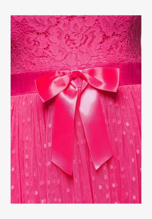 Robe en dentelle rose vif avec jupe en tulle à pois et large ruban en satin noué en nœud à la taille.