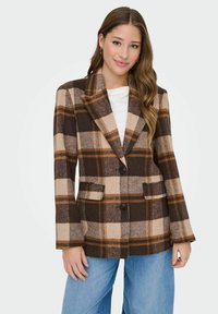 Blazer de cuadros en tonos marrón y beige, confeccionado en una mezcla de lana, con solapas de pico, dos bolsillos y cierre de botón, combinado con jeans de pierna ancha en color azul.