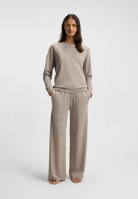 Hellbraunes Loungewear-Set mit locker sitzendem Langarmshirt und weitem Hosenbeinen, gefertigt aus weichem Material mit elastischem Bund.