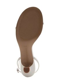 Białe sandały na wysokim obcasie z gładką, teksturowaną podstawą i okrągłym wycięciem na pięcie. Posiadają cienkie paski na kostkach oraz jednolitą podeszwę.