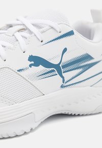 Bijela atletska tenisica s plavim akcentima, gornjište od mrežastog materijala i teksturiranim detaljima. Sadrži Puma logo i kontrastne pruge kroz dizajn.