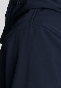 Marineblaue Jacke mit figurbetontem Schnitt, glatter Textur und kontrastierenden Nähten. Verstellbare Beschläge an der Kapuze für eine individuelle Passform.