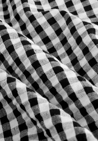 Tissu vichy noir et blanc présentant un motif à carreaux avec une texture douce, mettant en valeur un mélange de petits et de grands carrés.