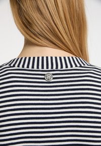 Mörkblå och vit randig skjorta med ribbad krage, som har en liten silverknapp med ett ankardesign på baksidan.