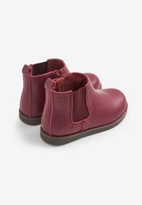 Botas de cuero burdeos hasta el tobillo con paneles laterales elásticos, punta redonda y sutiles detalles perforados a lo largo de los bordes superiores y las costuras.