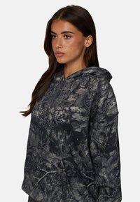 Bluza z kapturem w ciemnoszarym kolorze z wzorem kamuflażu, z kieszenią z przodu i teksturowanym materiałem.