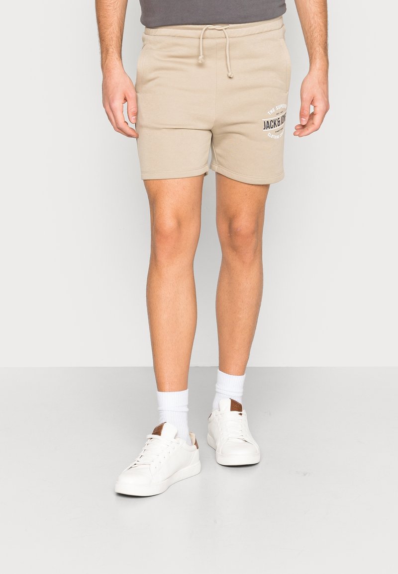 Beige bavlněné šortky s elastickým pasem a šňůrkou, s potiskem loga. V kombinaci s bílými teniskami a ponožkami do poloviny lýtek.