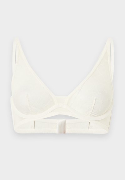 Λευκό σουτιέν με μαλακά κύπελλα, λεπτές ρυθμιζόμενες τιράντες, τριγωνικά κύπελλα και μπροστινό κούμπωμα με αγκράφα σε απλό φωτεινό φόντο.